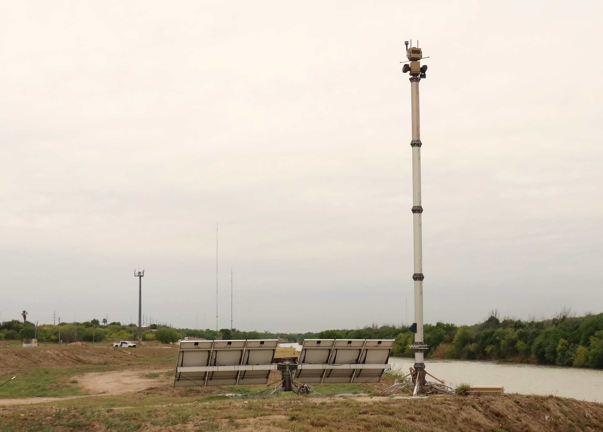 Two surveillance towers and a Border Patrol vehicle along the Rio Grande